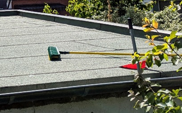 Ein Besen liegt während Reinigungsarbeiten auf einem Flachdach