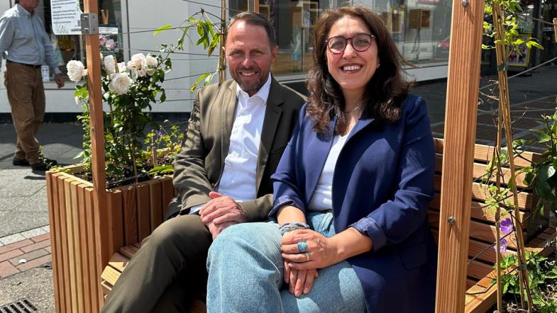 Fatma Özkan (Leiterung Gruppe Klimaanpassung VZ NRW) und Uwe Richrath (Oberbürgermeister Leverkusen) sitzen auf den Ausstellungsmöbeln