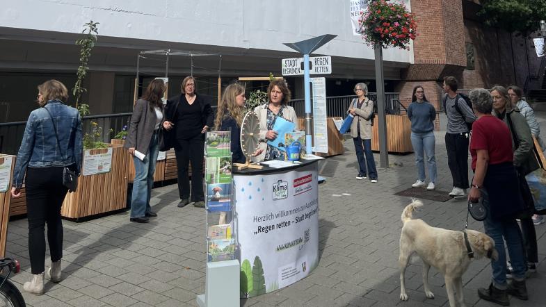 Veranstaltungstresen der Ausstellung mit Glücksrad und Menschen am Stand